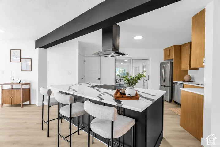 Kitchen featuring a large central island with a patterned countertop, a built-in range, and an overhead range hood