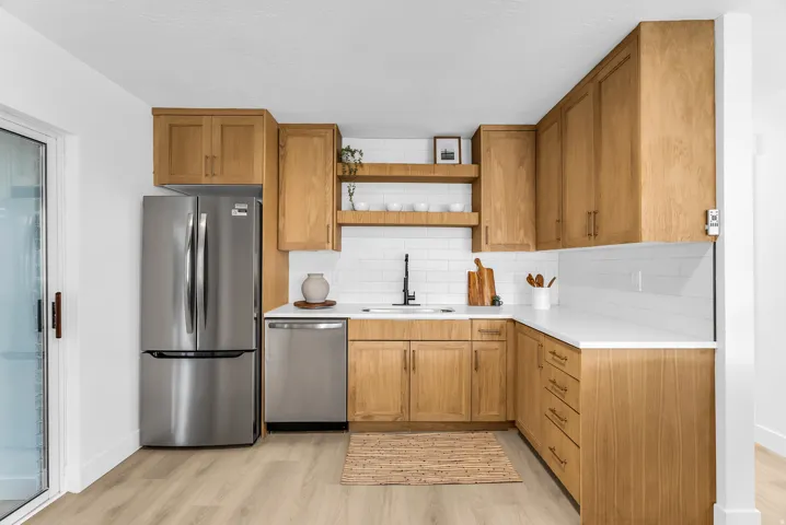 Kitchen featuring wood-finish cabinetry, white countertops, subway tile backsplash, and stainless steel appliances