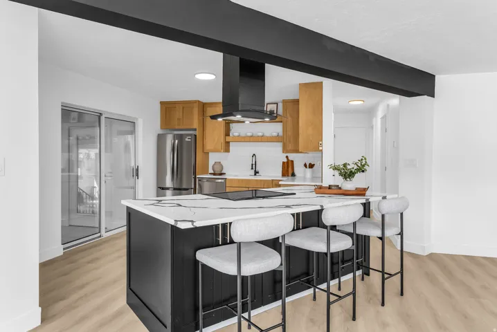 Kitchen island with a light-toned countertop, integrated cooktop, and black cabinetry