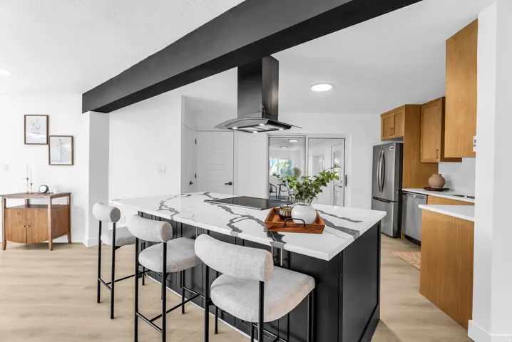 Kitchen featuring a large central island with a patterned countertop, a built-in range, and an overhead range hood
