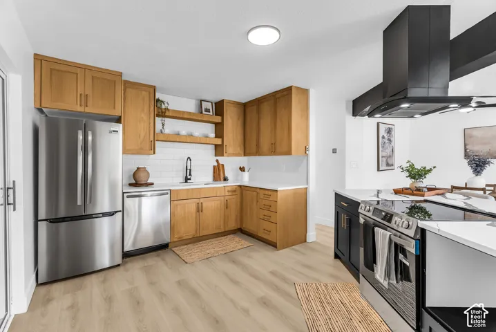 Kitchen featuring wood cabinetry, white subway tile backsplash, stainless steel appliances, and a black range hood