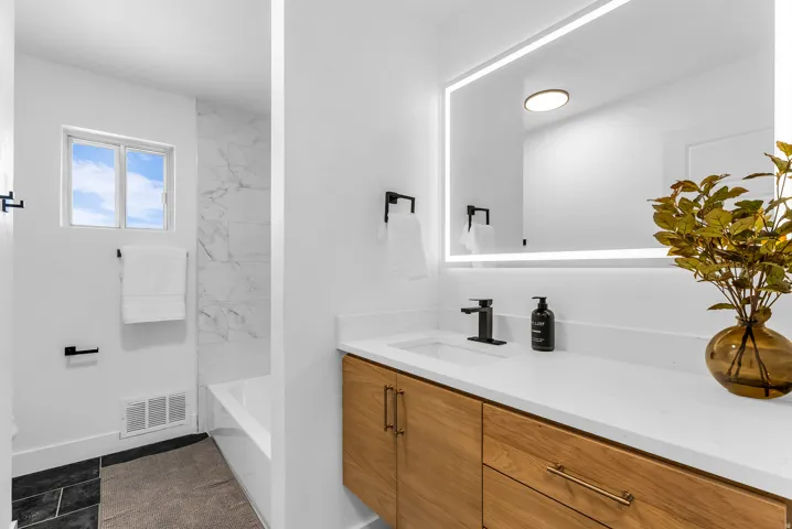 Modern vanity with wood-finish cabinetry, integrated sink, and matte black faucet