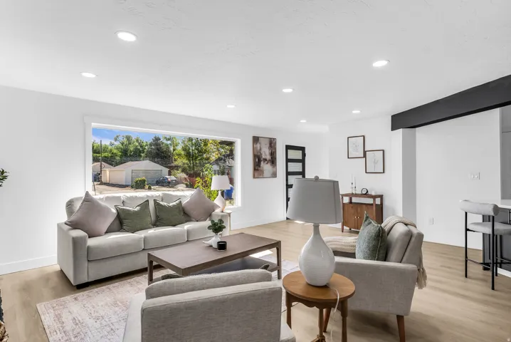 Recessed ceiling lighting, expansive window, wood-finish flooring, white walls, and a black accent beam
