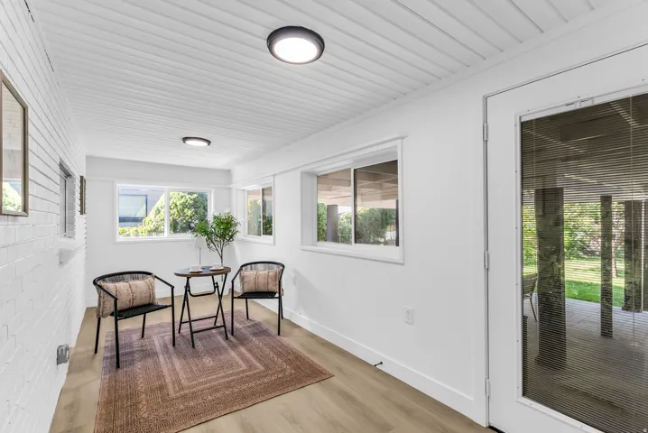 Bonus, green room, off from the kitchen. White plank ceiling with flush-mount lighting, light wood-finish flooring, white painted brick wall, and multiple windows