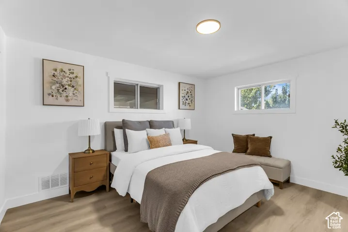 Bright room with white walls, wood-finish flooring, two windows, and a flush-mount ceiling light