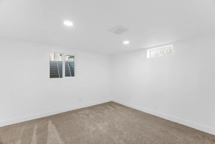 Third bedroom with neutral wall paint, recessed ceiling lighting, carpeted flooring, and two windows