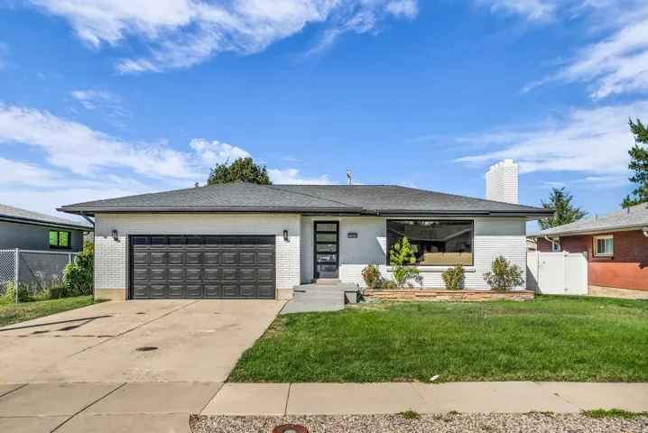 Contemporary ranch-style residence featuring a prominent front window, brick exterior, attached 2 garage, and a paved driveway