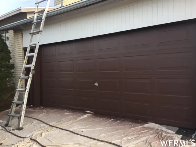 Brown panel garage door with a white horizontal siding accent
