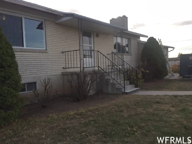 Brick exterior with an elevated entry, concrete porch, and black metal railings