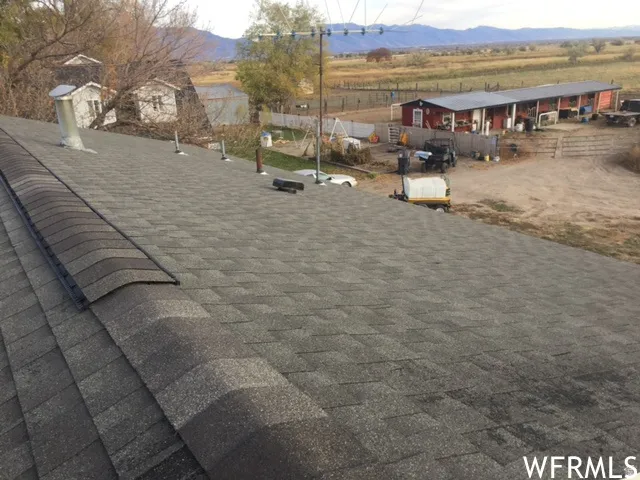 Asphalt shingle roof with ridge vent, featuring a visible chimney and various roof vents