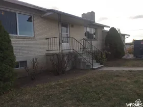 Brick exterior with white window frames, concrete steps, and black metal handrails