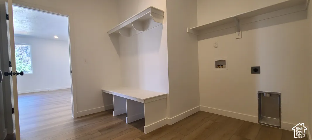 Built-in storage bench with overhead shelving, wood-finish flooring, and laundry hookups