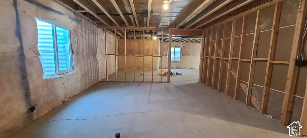 Unfinished interior space with exposed ceiling joists, concrete flooring, and framed wall partitions