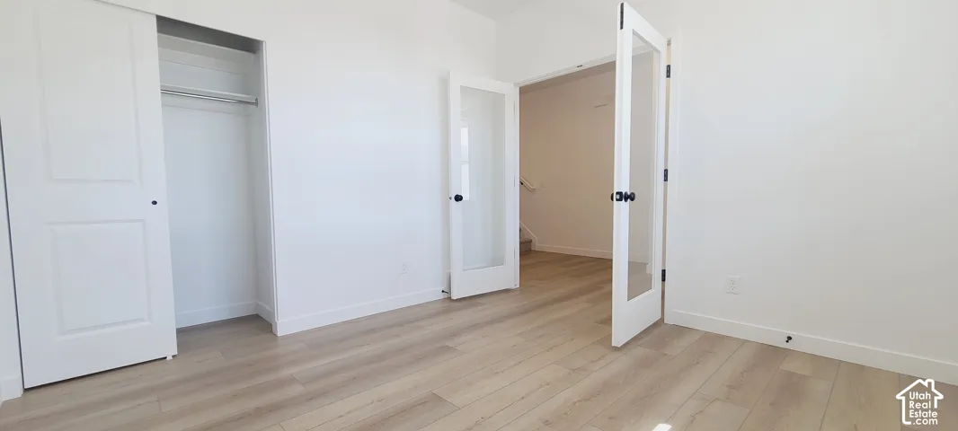 Light wood-finish flooring, white walls, and a built-in closet with sliding doors