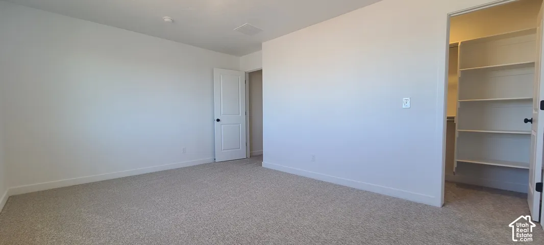 Carpeted room with white walls, a white two-panel door, and an open closet with built-in shelving