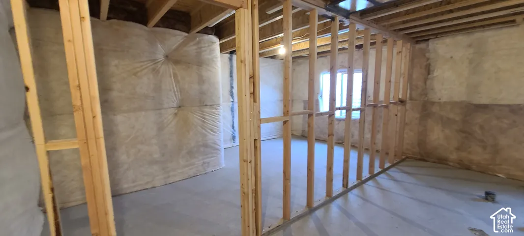 Unfinished basement with exposed wood framing, concrete flooring, and visible insulation