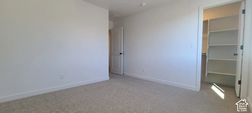 Neutral tone walls and carpeting, offering a built-in closet with shelving and a solid core door with matte black hardware