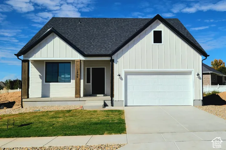 Modern farmhouse exterior featuring vertical board-and-batten siding, contrasting dark roof shingles, timber-finish porch columns, and an attached two-car garage