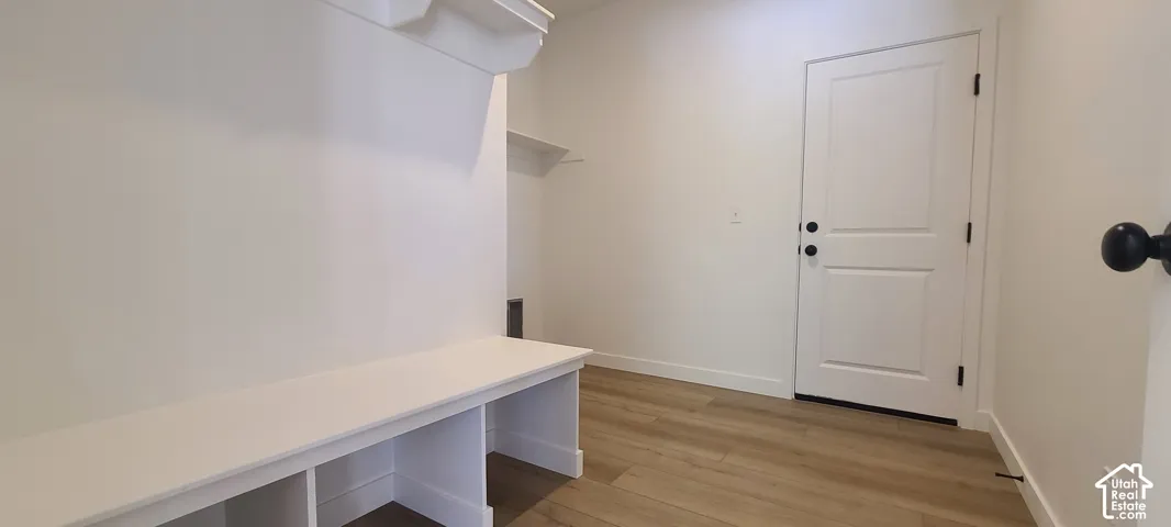 Built-in bench seating with cubby storage, a white panel door with black hardware, and wood-finish flooring