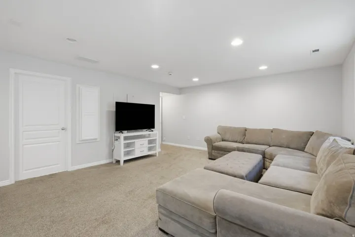 Recessed lighting, light gray wall paint, neutral-toned carpeting, and a white paneled door