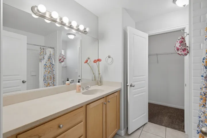 Neutral-toned vanity with an integrated sink, broad wall-mounted mirror, and overhead vanity lighting
