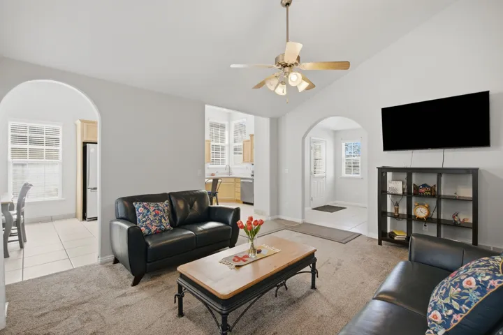Vaulted ceilings, archway entries, and a ceiling fan with integrated lighting