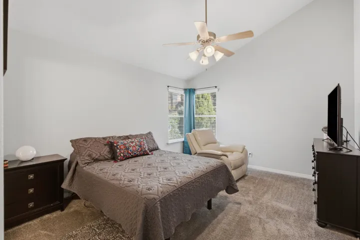 Vaulted ceiling, ceiling fan with integrated lighting, carpet flooring, window with blinds, and white wall finishes