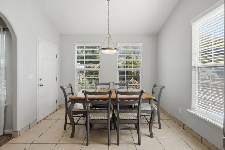 High ceilings, tiled flooring, pendant lighting fixture, white paneled door, and multiple windows