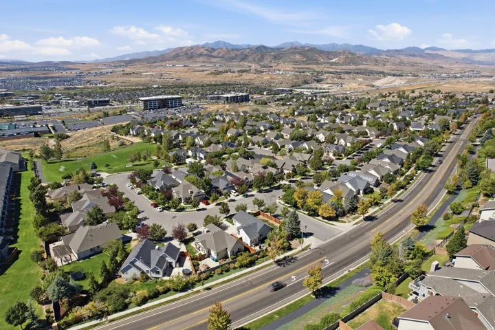 Residential neighborhood with varied architectural styles, mature trees, and a mountain backdrop