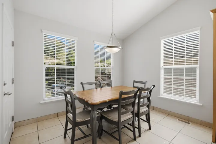 Vaulted ceiling, three large windows, a flush-mount light fixture, and tile flooring