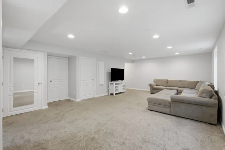 Recessed lighting illuminates this carpeted space featuring multiple paneled doors and light gray walls