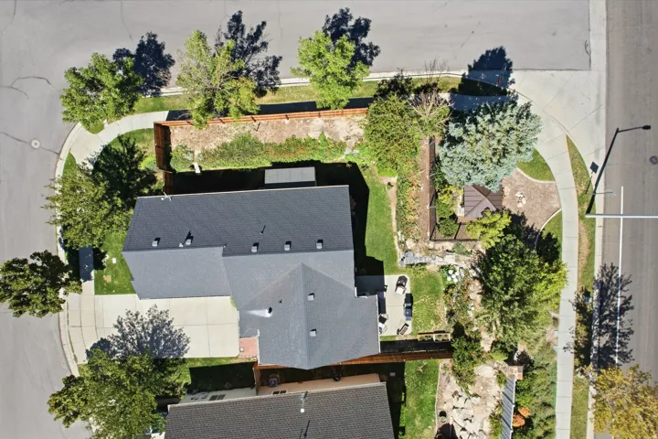 Paved driveway and walkways, dark shingle roof, mature landscaping, and an exterior patio with a gazebo