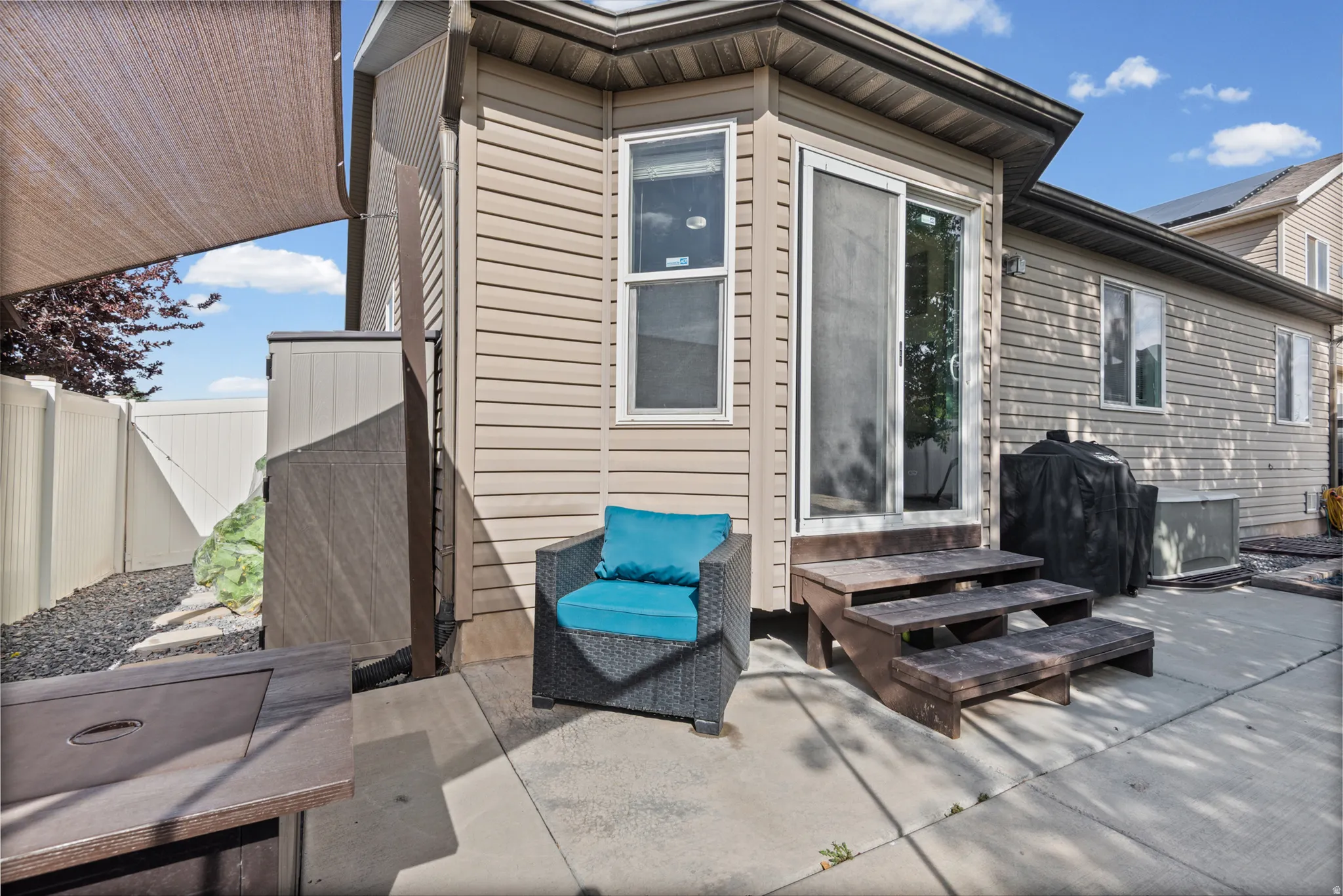 Concrete patio area featuring a sliding glass door and steps, with tan siding on the property exterior