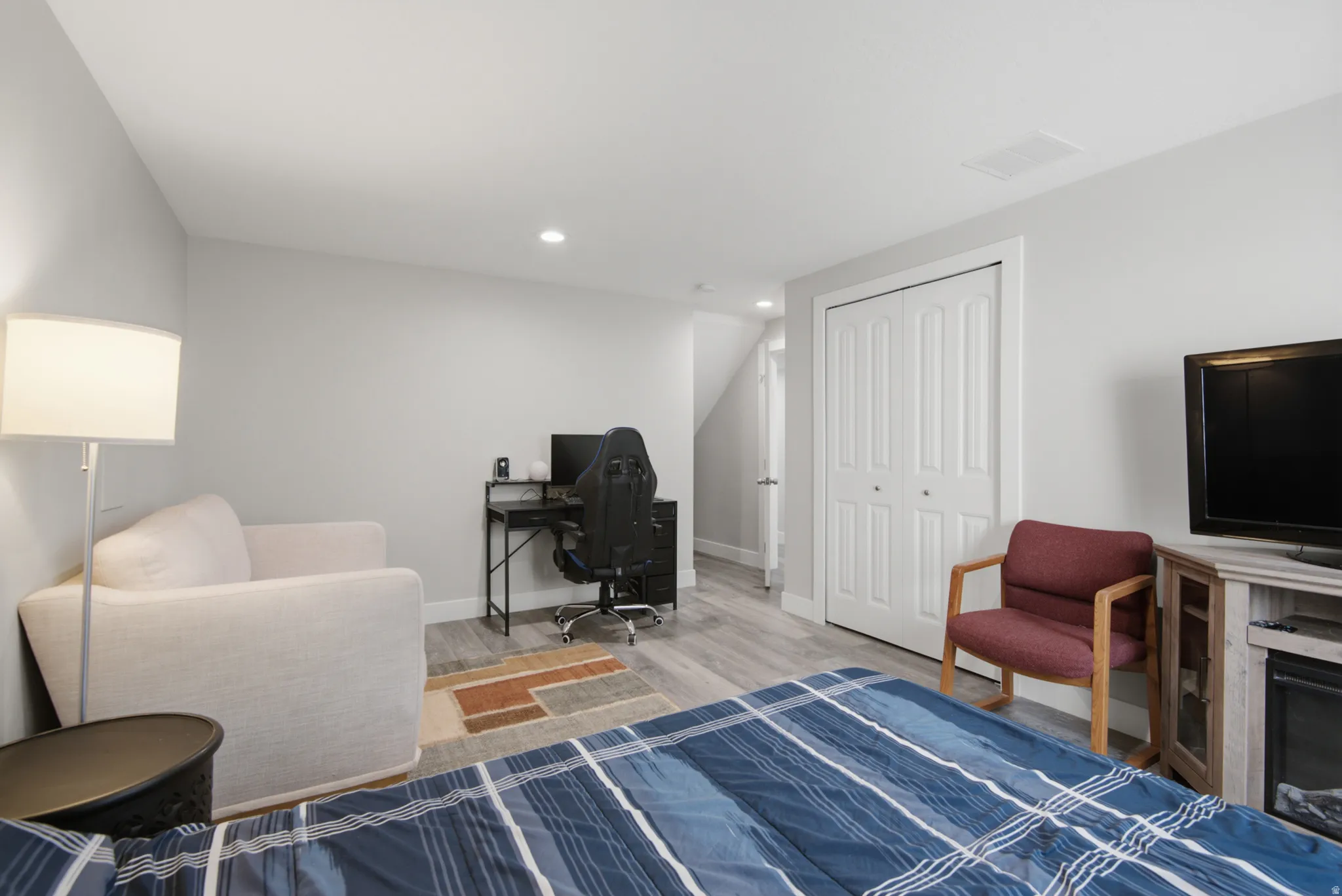 Recessed ceiling lighting, wood-finish flooring, light gray wall finishes, and white bi-fold closet doors