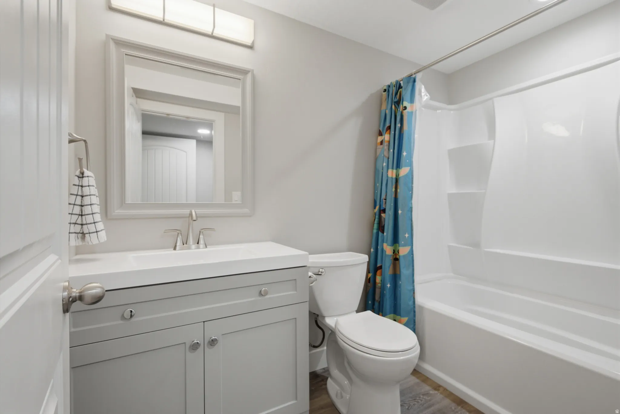 White vanity with a single basin sink, brushed nickel faucet, framed mirror, and integrated lighting