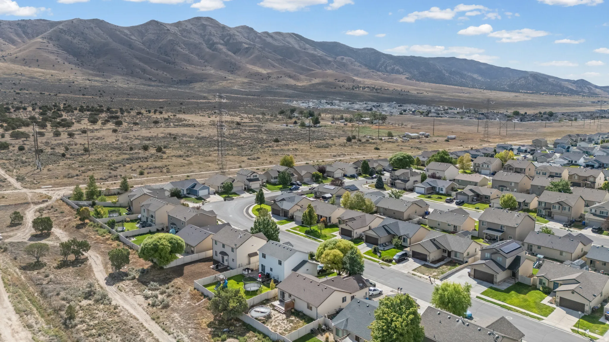 Residential neighborhood with paved streets and established homes, set against a backdrop of distant mountains