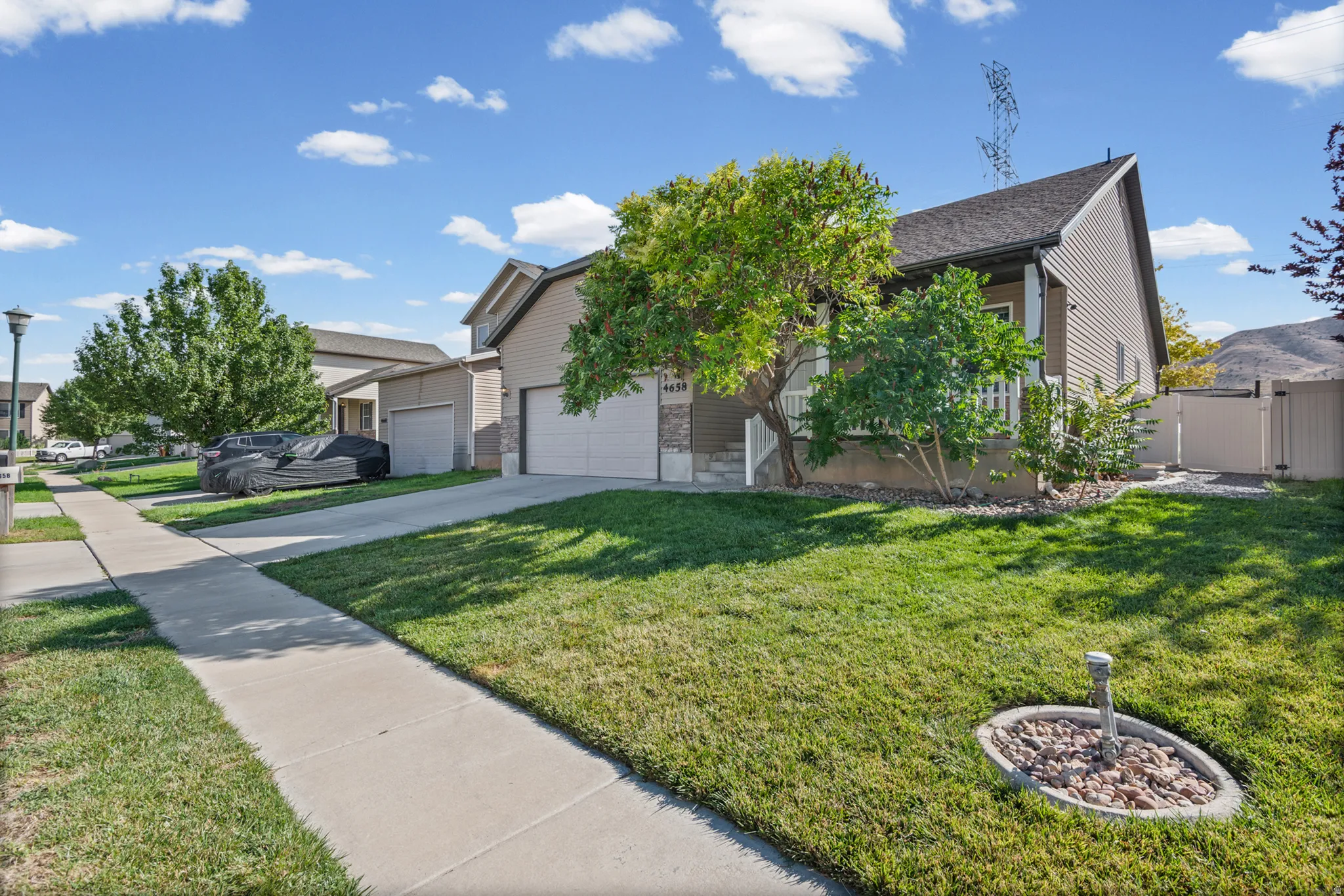 Exterior featuring siding and stone accents, two-car garage, manicured lawn, and privacy fencing