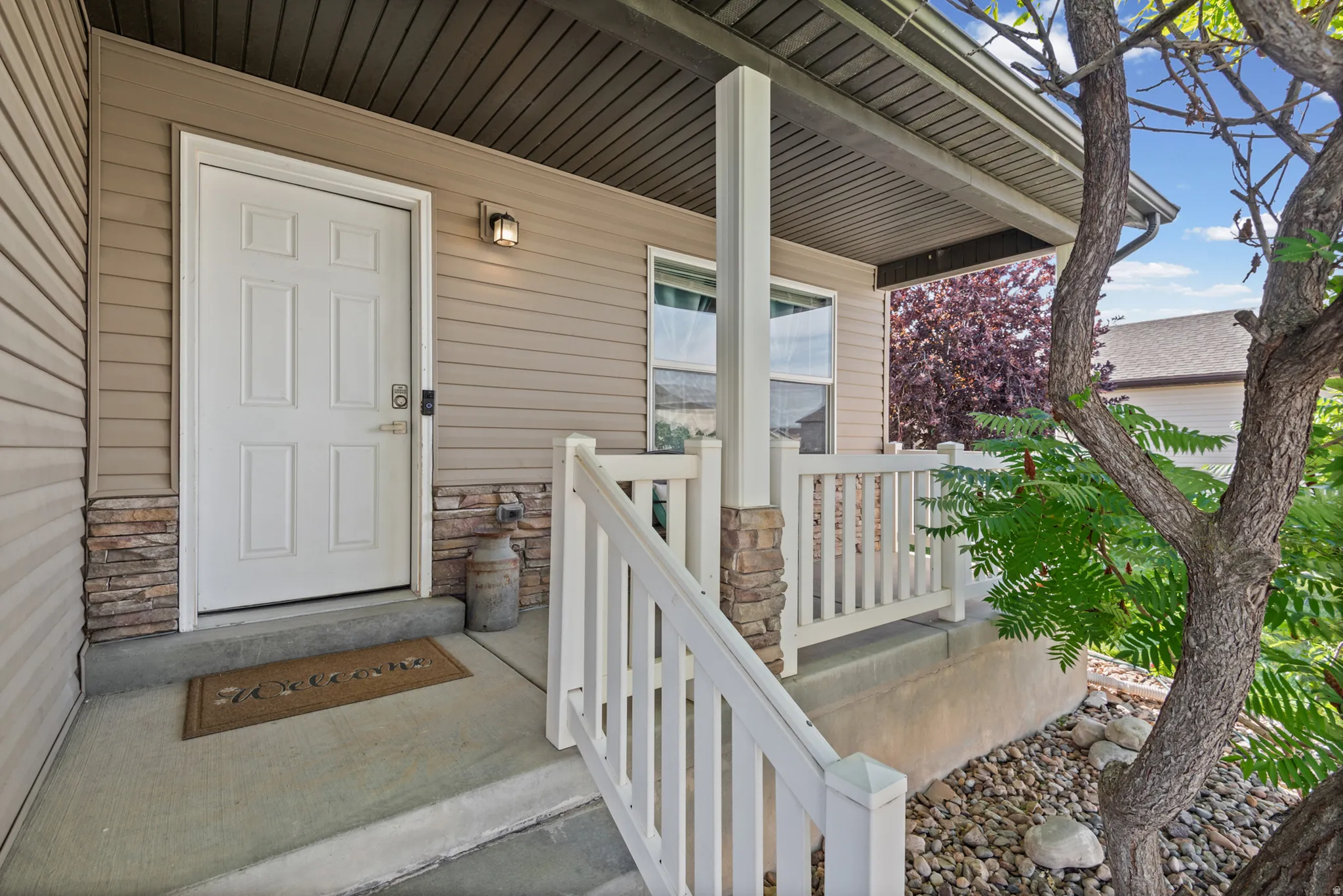 Covered entry with concrete flooring, stone accents, and a white paneled door