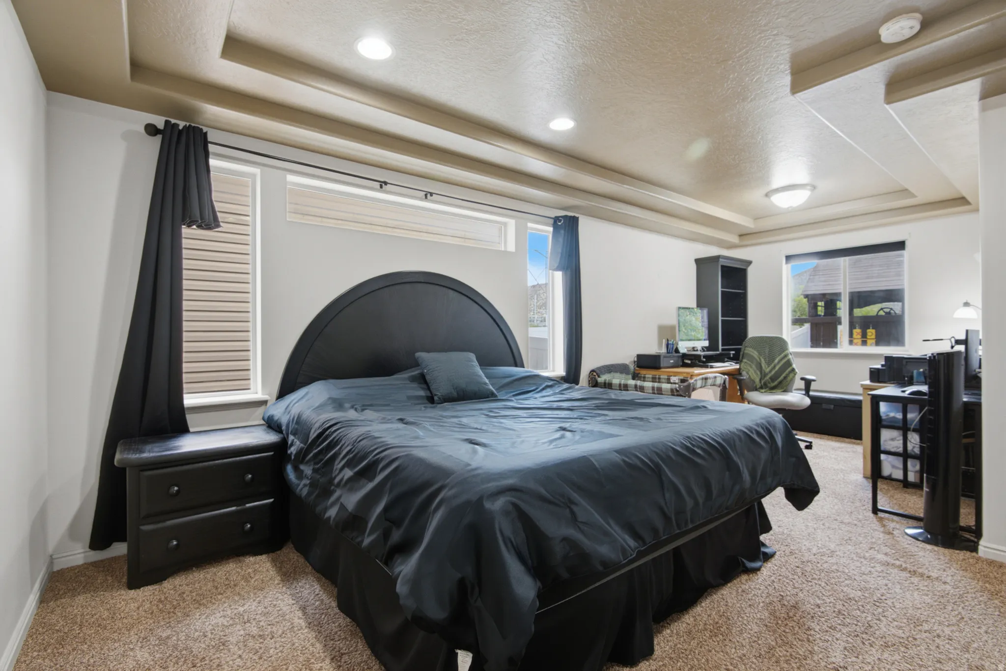 Recessed lighting, tray ceiling, carpet flooring, windows with blinds, built-in shelving