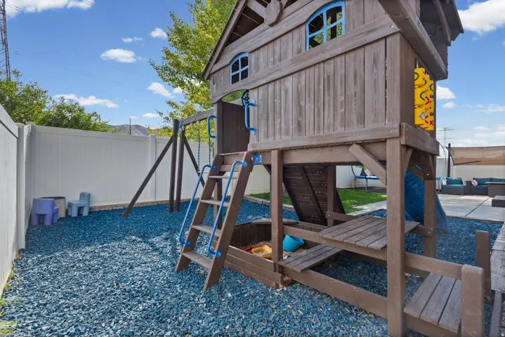 Outdoor play structure featuring a slide, swings, and a climbing wall