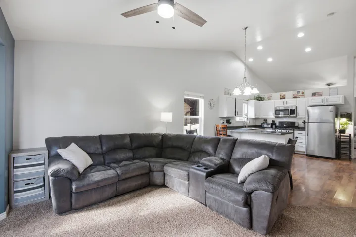 Vaulted ceiling with recessed lighting, kitchen with white cabinetry, stainless steel appliances, wood-finish flooring, and a ceiling fan