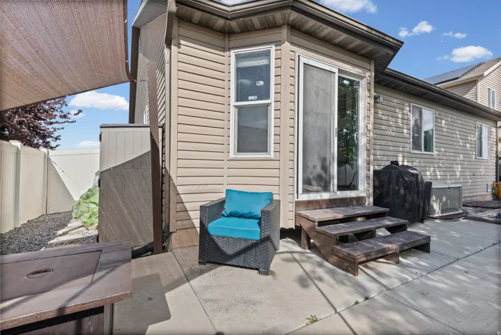 Concrete patio area featuring a sliding glass door and steps, with tan siding on the property exterior