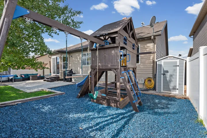 Expansive backyard featuring a patio, a detached storage shed, privacy fencing, and a permanent play structure