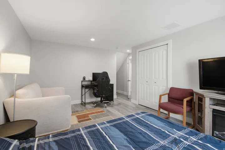 Recessed ceiling lighting, wood-finish flooring, light gray wall finishes, and white bi-fold closet doors