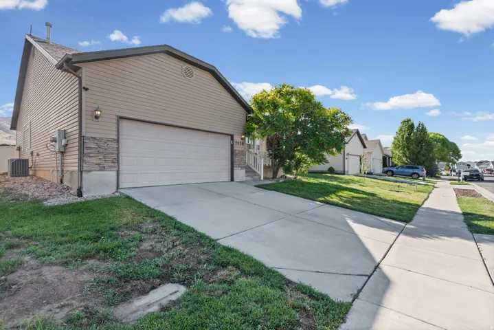 Siding exterior with stone veneer accents, attached garage, concrete driveway, and front yard landscaping