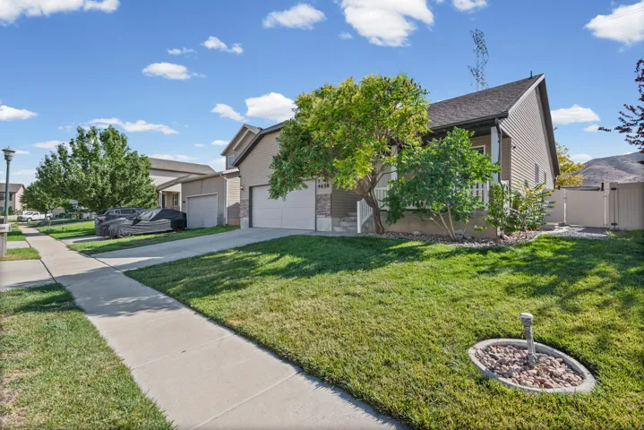 Exterior featuring siding and stone accents, two-car garage, manicured lawn, and privacy fencing