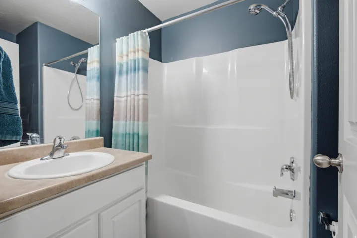 White vanity with integrated sink, chrome faucet, and mirrored wall