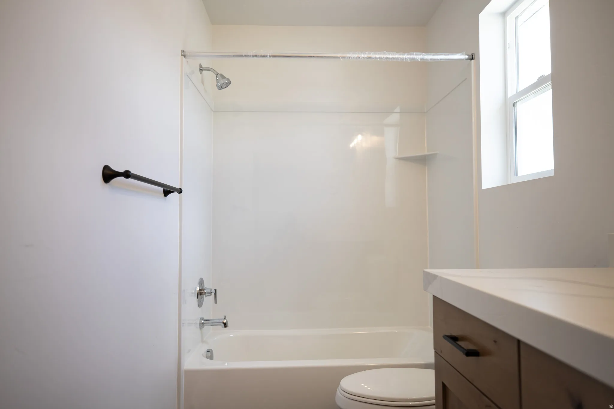 Full secondary bath with stained wood cabinet, extra-long vanity and quartz slab countertops.