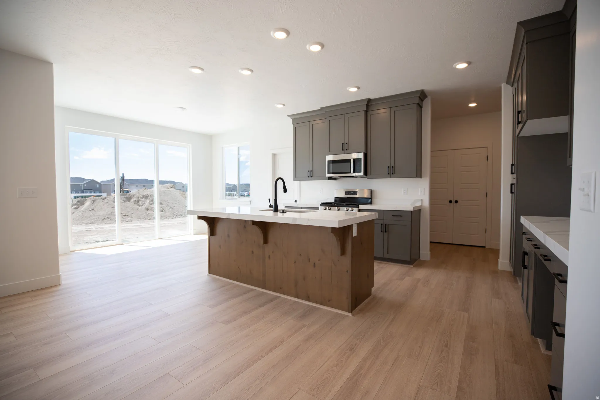 Open dining area with sliding glass door and picture windows adjacent to kitchen and large walk-in pantry.