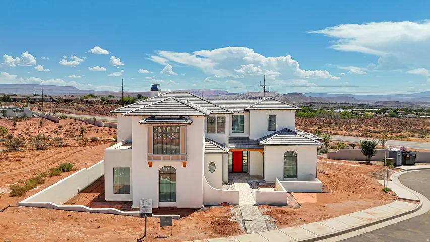 Two-story stucco exterior with a tile roof, an arched entry, a red front door, and multiple window styles